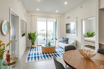 Living room in our 2-bedroom model with a blue and white rug, a wooden table, and a white couch at Hollywood Heights on the Boulevard Luxury Apartments in Hollywood, FL